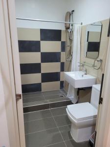 a bathroom with a white toilet and a sink at La Belle Staycation in Puerto Princesa City