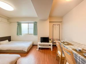 大阪市にあるREIWA HOUSEのベッド2台、テーブル、テレビが備わる客室です。
