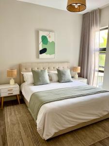 a white bedroom with a large bed and a window at Tropical beachfront apartment in Belle Mare
