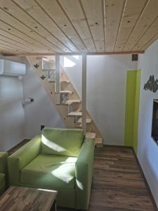 sala de estar con sofá verde y escaleras en Ергини en Dobrinishte