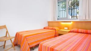 Habitación con 3 camas, silla y ventana en Mas Vermey nº 4, en Calella de Palafrugell