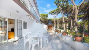 Un patio con una mesa y sillas blancas y árboles. en Mas Vermey nº 4, en Calella de Palafrugell