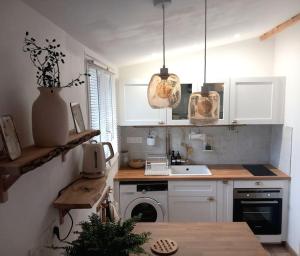 kuchnia z białymi szafkami, zlewem i kuchenką w obiekcie Gîte au cœur des châteaux de la Loire w mieście Cellettes