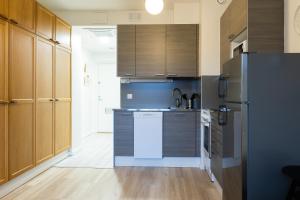 a kitchen with wooden cabinets and a refrigerator at Studio apartment in central Turku in Turku