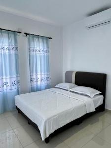 una camera da letto con un letto con lenzuola bianche e tende blu di Bayu Laut Homestay a Malacca