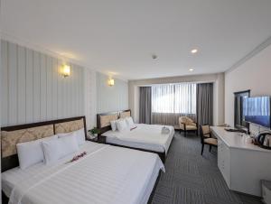 ein Hotelzimmer mit 2 Betten und einem TV in der Unterkunft Đông Kinh Hotel in Ho-Chi-Minh-Stadt