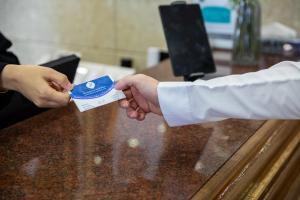 una persona está entregando a otra persona un pedazo de papel en Hyatt Jeddah Continental Hotel, en Yeda