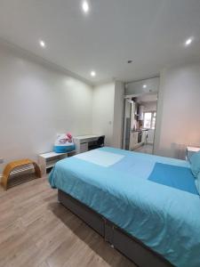 a bedroom with a large blue bed and a kitchen at Cosy Entire Home Kingscross Central London in London