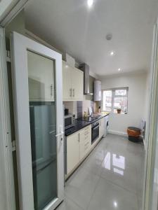 a kitchen with white cabinets and a large glass door at Cosy Entire Home Kingscross Central London in London