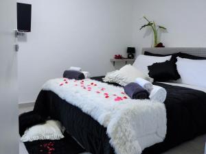 Una cama blanca y negra con flores rojas. en Casa Maia, en Casalabate