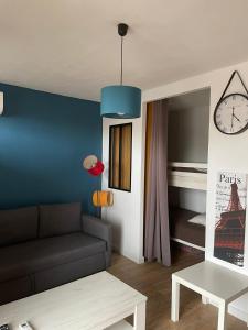 un soggiorno con divano e orologio sul muro di Superbe studio à Canet en Roussillon proche de la plage a Canet-en-Roussillon