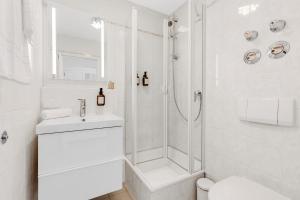 ein weißes Bad mit einer Dusche und einem Waschbecken in der Unterkunft Casa Hirsch - Zentral, Bergblick, TV, Nespresso in Miesbach