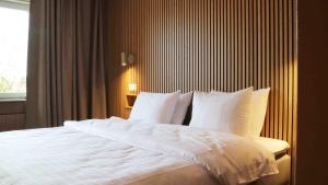 a bedroom with a bed with white sheets and a window at Medlefors Hotell & Konferens in Skellefteå