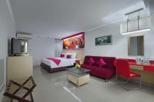 uma sala de estar com um sofá vermelho e uma cama em favehotel Premier Cihampelas em Bandung