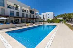 een zwembad voor een gebouw bij Apartment La Nau - Fantastic Apartment with hot tub and pool, just steps away from beach in Port de Pollença