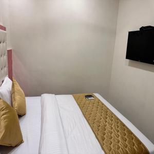 a bedroom with a bed with a television on the wall at Hotel Airport Crown - Near Mumbai International Airport T-2 in Mumbai