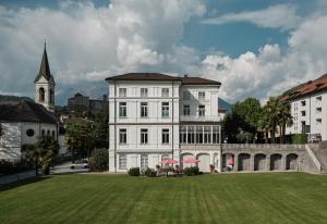 un grand bâtiment blanc avec une pelouse devant lui dans l'établissement Business Center IN Villa, à Bellinzone