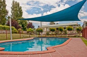 einen Pool mit blauem Regenschirm darüber in der Unterkunft Warragul Gardens Holiday Park in Warragul