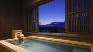 una piscina con una ventana con vistas a la ciudad en Yoshidaya Sannoukaku en Kaga