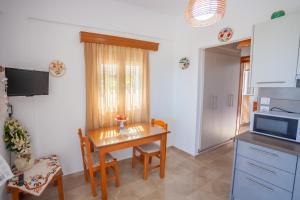 eine Küche mit einem Tisch, Stühlen und einer Mikrowelle in der Unterkunft Kavousanos Apartments in Istro