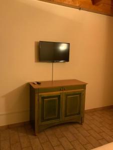 TV de pantalla plana en la pared con armario de madera en ConcaverdeClub, en Sogliano al Rubicone