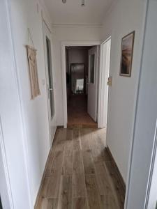 um corredor com paredes brancas e piso de madeira em Petite maison chaleureuse avec parking em Leuze-en-Hainaut
