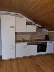 a kitchen with white appliances and a wooden ceiling at Ferienhof Altmann in Arrach