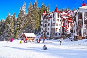 a group of people in the snow in front of buildings at ЗАМЪКА 1 in Pamporovo