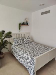 uma cama num quarto branco com uma colcha e uma planta em Estudio Puerto de Sotogrande em San Roque