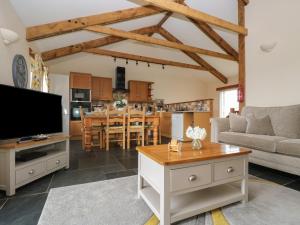 a living room and kitchen with a flat screen tv at Hawthorn Cottage in Truro