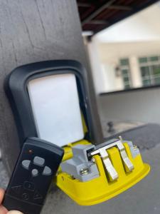 a person holding a remote control next to a pay phone at NO 121 NAZIRIN HOMESTAY TMN DESA MANJUNG in Lumut +6 photos