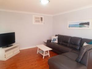 a living room with a couch and a tv at Watts @ Callala Beach-Pet Friendly in Callala Beach