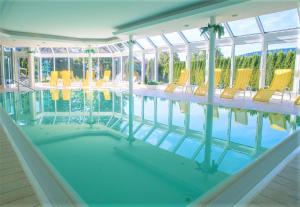 an indoor swimming pool with yellow chairs in it at Appartement Sunset, 28qm in Schluchsee