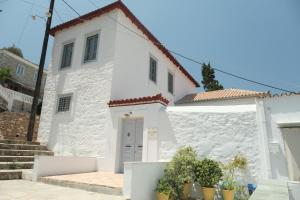 a white house with plants in front of it at Metochi Athentic Hospitality in Hydra
