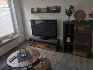 a living room with a flat screen tv and a table at Ferienwohnung Lüttje Delftblick in Emden