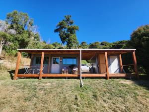 een huis met een veranda rondom in een veld bij Glenwood Akaroa Bush Retreat - Kanuka Hut in Akaroa