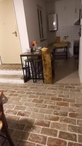 eine Küche mit Backsteinboden und einem Tisch in der Unterkunft CASA DEL MAESTRO in Castel di Lama
