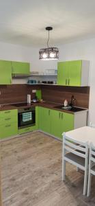 cocina con armarios de color verde lima, mesa y lámpara de araña en Apartmán Burger, en Terchová