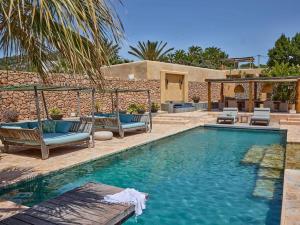 a swimming pool with chairs and a house at Kasbah Darshan in Cala Vadella