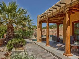 a wooden walkway leading to a house with a palm tree at Kasbah Darshan in Cala Vadella