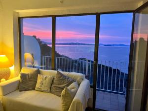 Sofá blanco sentado en un balcón con vistas al océano en Apartamento con playa y vistas en la Costa Brava en Begur