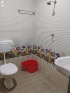 a bathroom with a toilet and a sink and flowers on the wall at Vishram Homestay, Malpe Beach, Udupi in Malpe