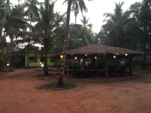 a hut with tables and palm trees in a field at Vishram Homestay, Malpe Beach, Udupi in Malpe