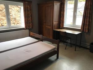 a bedroom with a bed and a desk and windows at Centre Louis Delobbe in Olloy-sur-Viroin