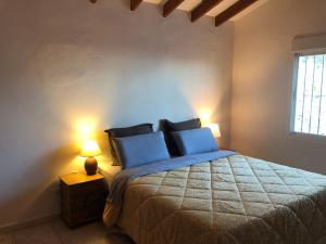 a bedroom with a bed with blue pillows and two lamps at Panoramavilla Lofio Spain in Cómpeta