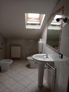 een badkamer met een wastafel, een toilet en een spiegel bij Le mansarde di Via Isonzo in Chieti