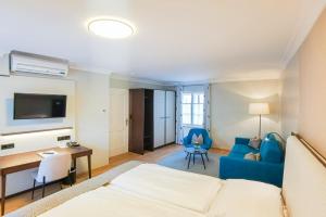a room with a bed and a desk and a couch at Hotel Elefant in Salzburg