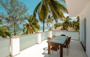 uma varanda com uma mesa e cadeiras e o oceano em Imani Penthouse - Private Beachfront apartment with Spectacular Ocean Views em Kiwengwa