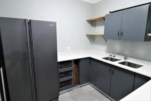 a kitchen with black cabinets and a stainless steel refrigerator at DE KELDERS HOUSE in De Kelders