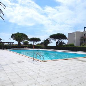 una gran piscina con árboles en el fondo en Les Capitelles : Appartement vue montagne en residence avec piscine -sur le front de mer en Saint-Cyprien